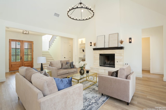 living room with built in shelves, french doors, high vaulted ceiling, a fireplace, and light wood-type flooring