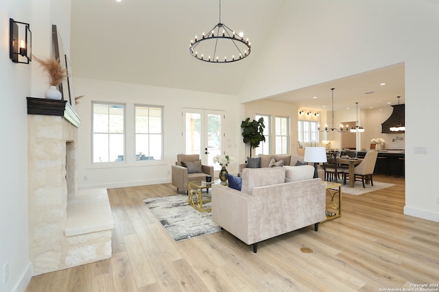 living room with light wood-type flooring, an inviting chandelier, and high vaulted ceiling