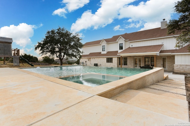 view of pool with an in ground hot tub, pool water feature, and a patio area