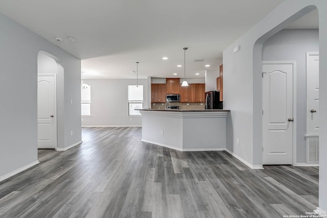 kitchen featuring black refrigerator, hardwood / wood-style floors, decorative light fixtures, and kitchen peninsula