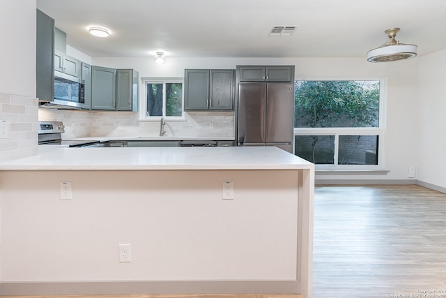 kitchen featuring backsplash, kitchen peninsula, sink, and appliances with stainless steel finishes