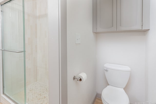 bathroom with a shower with shower door and toilet