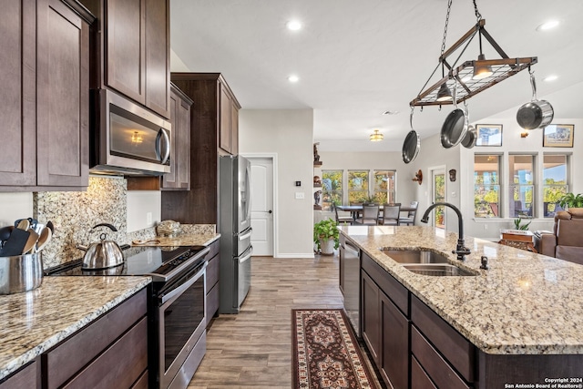 kitchen featuring light stone countertops, appliances with stainless steel finishes, a kitchen island with sink, sink, and light hardwood / wood-style floors