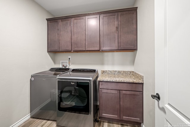 laundry area with hardwood / wood-style floors, cabinets, and washing machine and dryer