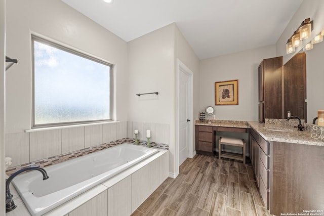 bathroom with hardwood / wood-style flooring, vanity, and a washtub