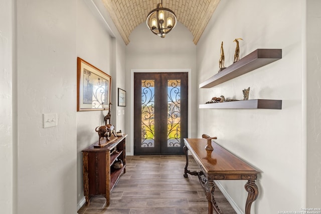 foyer with lofted ceiling, french doors, dark hardwood / wood-style flooring, brick ceiling, and a chandelier