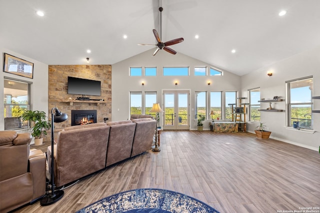 living room with ceiling fan, french doors, high vaulted ceiling, light hardwood / wood-style floors, and a fireplace