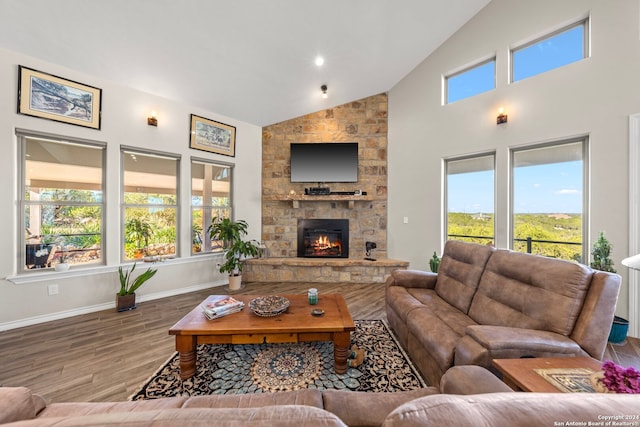 living room featuring hardwood / wood-style flooring, a healthy amount of sunlight, a fireplace, and high vaulted ceiling