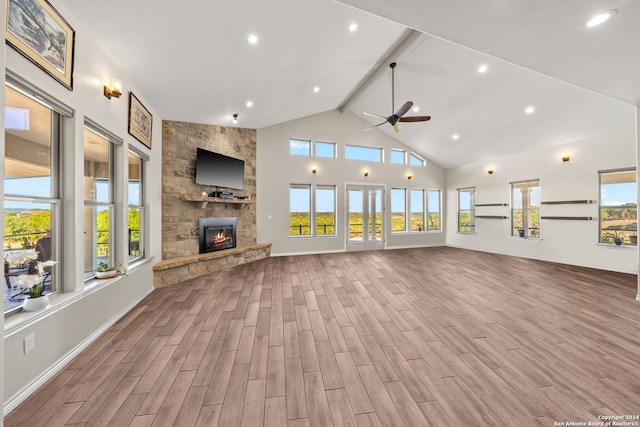 unfurnished living room with beam ceiling, ceiling fan, high vaulted ceiling, a fireplace, and light wood-type flooring