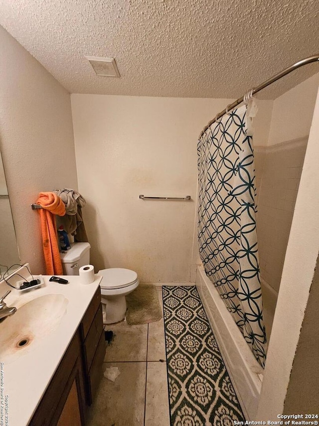 bathroom featuring a shower with shower curtain, vanity, a textured ceiling, tile patterned flooring, and toilet