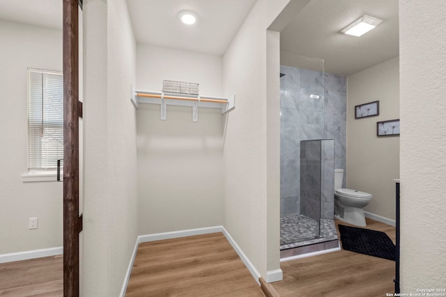 bathroom featuring tiled shower, hardwood / wood-style floors, and toilet