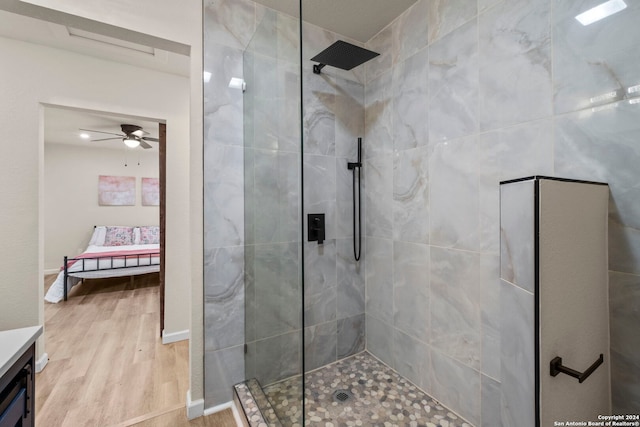 bathroom with tiled shower, hardwood / wood-style floors, vanity, and ceiling fan