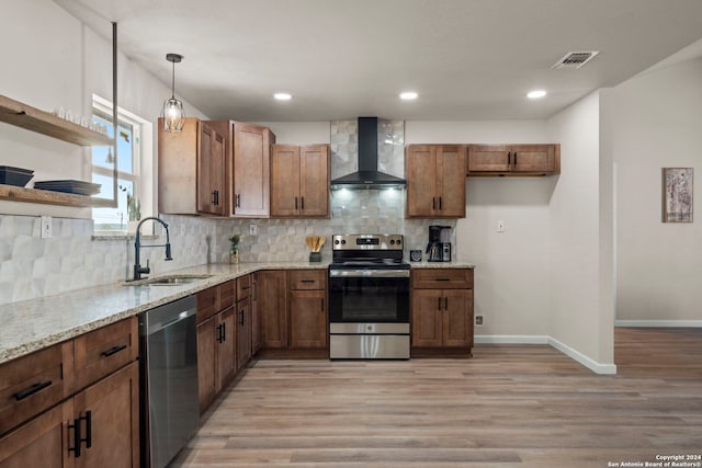 kitchen with light wood-type flooring, stainless steel appliances, wall chimney exhaust hood, and sink