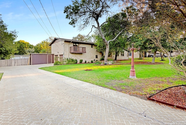 view of front facade featuring a balcony, an outbuilding, and a front lawn