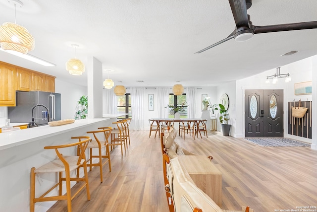 kitchen with pendant lighting, light hardwood / wood-style flooring, high quality fridge, and lofted ceiling