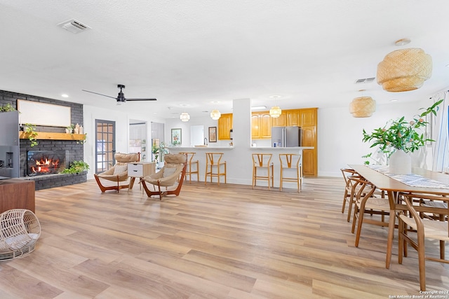 living room featuring a brick fireplace, ceiling fan, and light hardwood / wood-style flooring