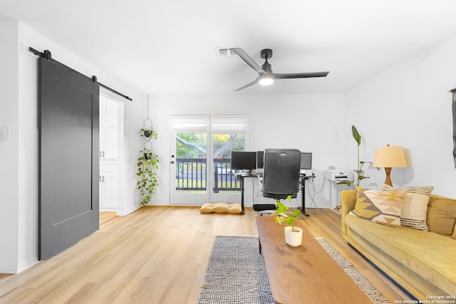 interior space with a barn door, ceiling fan, and light hardwood / wood-style flooring