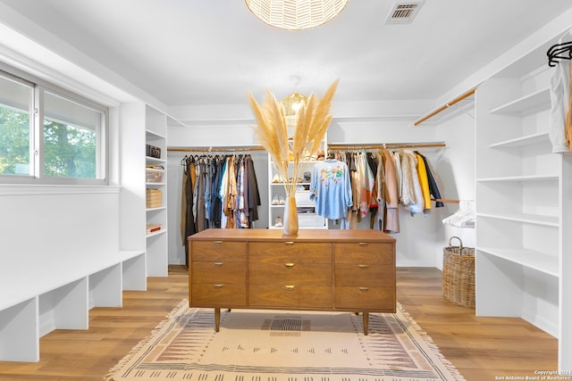 walk in closet with light hardwood / wood-style floors