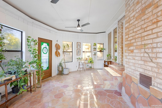 unfurnished sunroom with ceiling fan