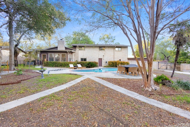 rear view of house featuring a patio area and a fenced in pool