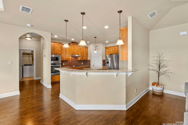 kitchen featuring a breakfast bar, backsplash, dark wood-type flooring, appliances with stainless steel finishes, and kitchen peninsula