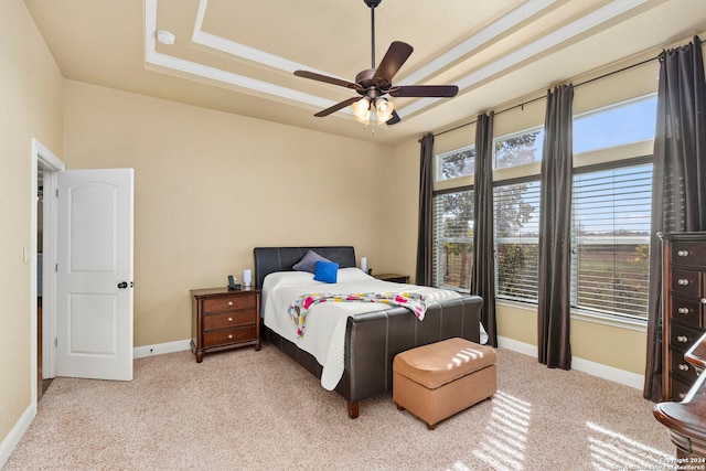 bedroom with ceiling fan, a raised ceiling, and light carpet