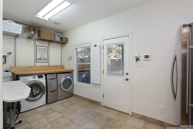 laundry area with washing machine and clothes dryer and light tile patterned floors