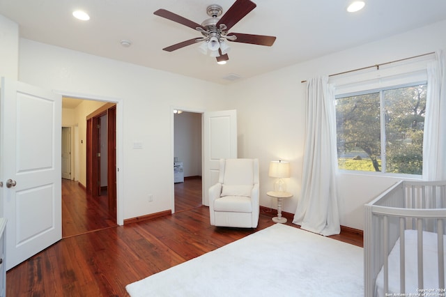 bedroom featuring ceiling fan, dark hardwood / wood-style flooring, and a crib