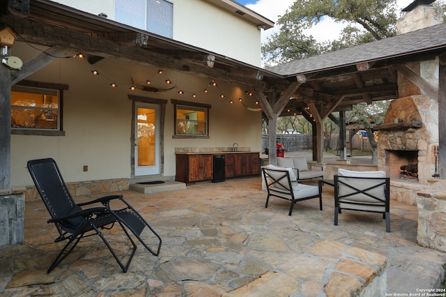 view of patio with an outdoor stone fireplace, sink, and exterior kitchen