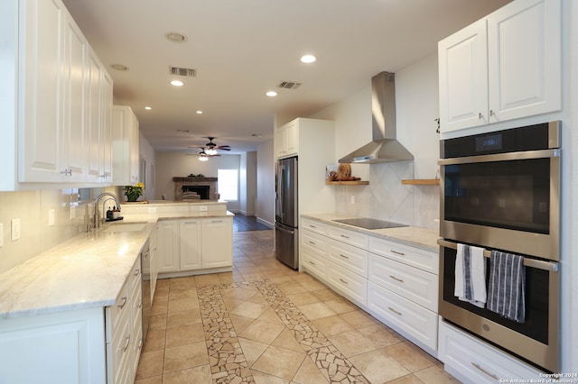 kitchen featuring white cabinets, wall chimney range hood, and appliances with stainless steel finishes