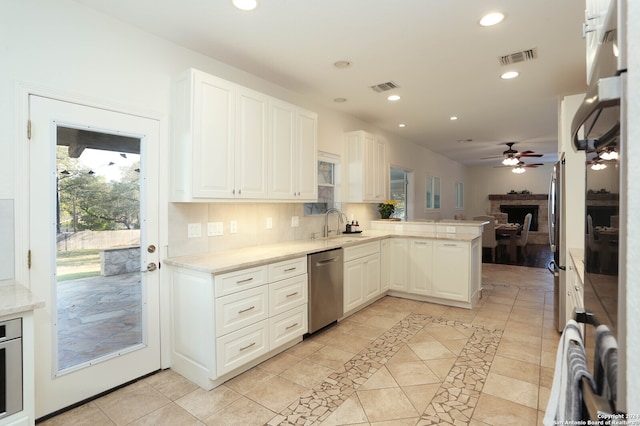 kitchen with backsplash, kitchen peninsula, ceiling fan, appliances with stainless steel finishes, and white cabinetry