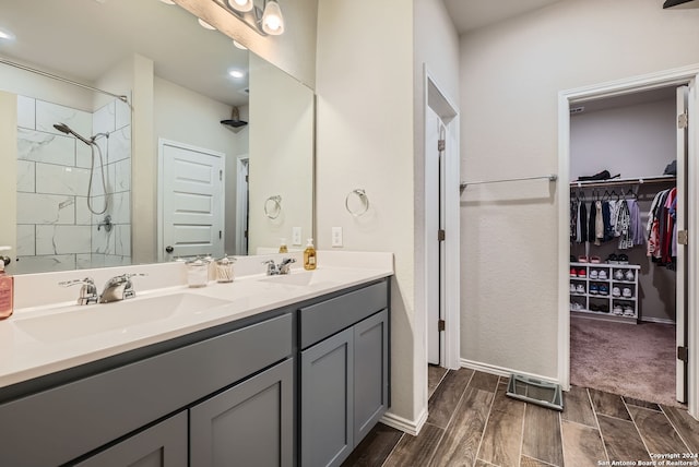 bathroom featuring hardwood / wood-style floors, vanity, and a tile shower