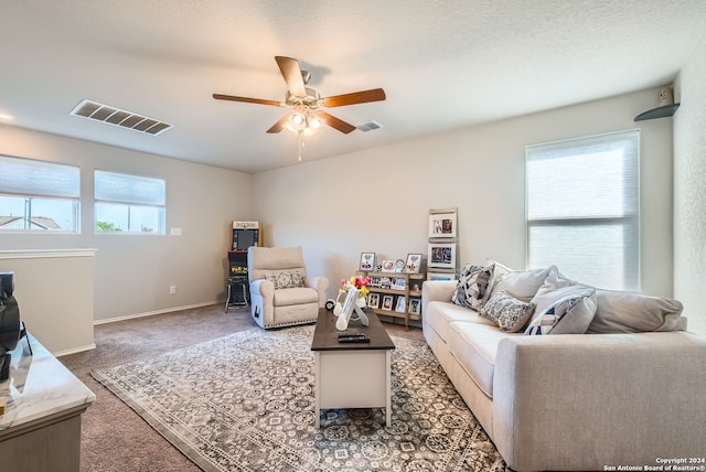 living room with a textured ceiling, dark carpet, and ceiling fan