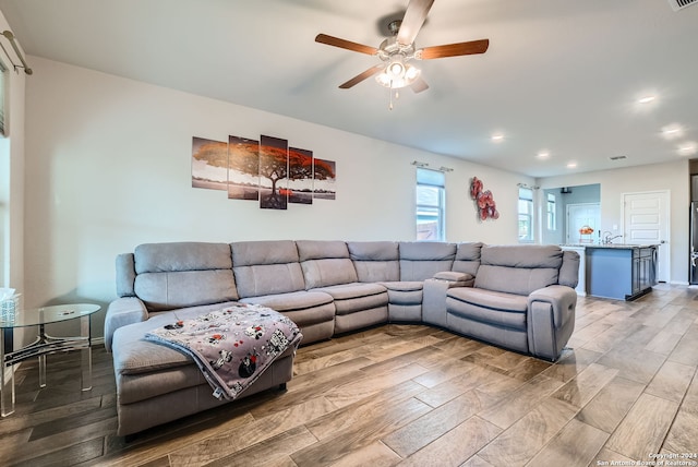 living room with ceiling fan, light hardwood / wood-style floors, and sink