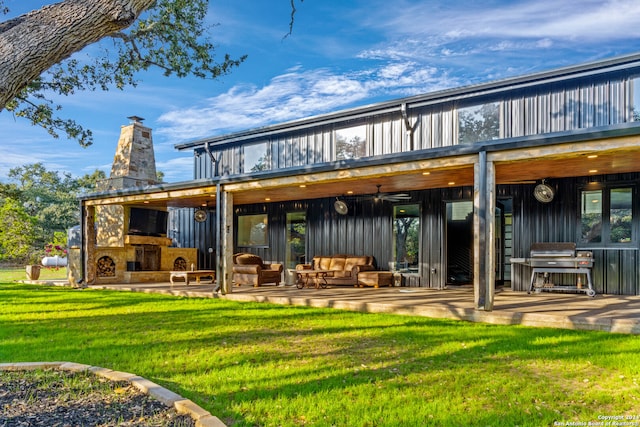 rear view of house with an outdoor living space with a fireplace, a patio area, ceiling fan, and a yard