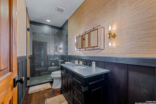 bathroom with walk in shower, toilet, vanity, tile walls, and hardwood / wood-style flooring