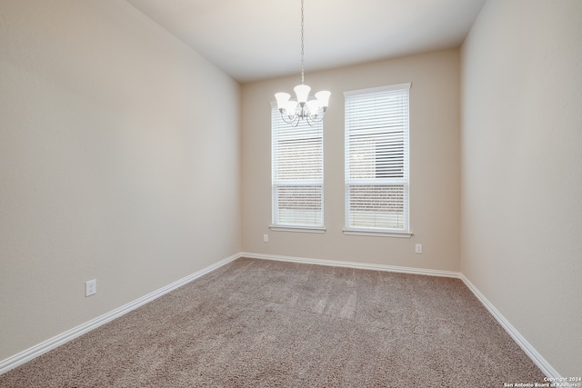 spare room with a wealth of natural light, carpet, and a notable chandelier