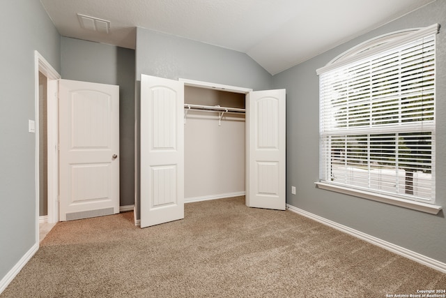 unfurnished bedroom featuring a closet, carpet, and lofted ceiling