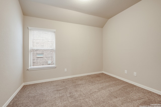 carpeted empty room featuring lofted ceiling and a textured ceiling