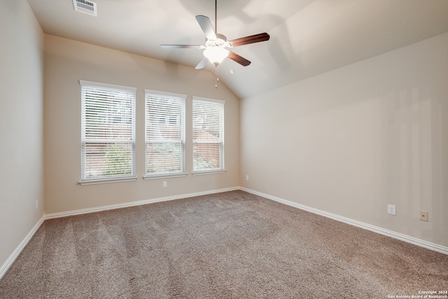 empty room featuring carpet flooring, vaulted ceiling, plenty of natural light, and ceiling fan