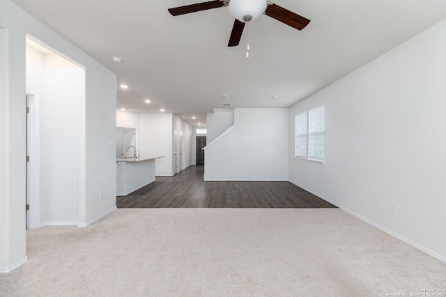 unfurnished living room featuring ceiling fan, wood-type flooring, and sink