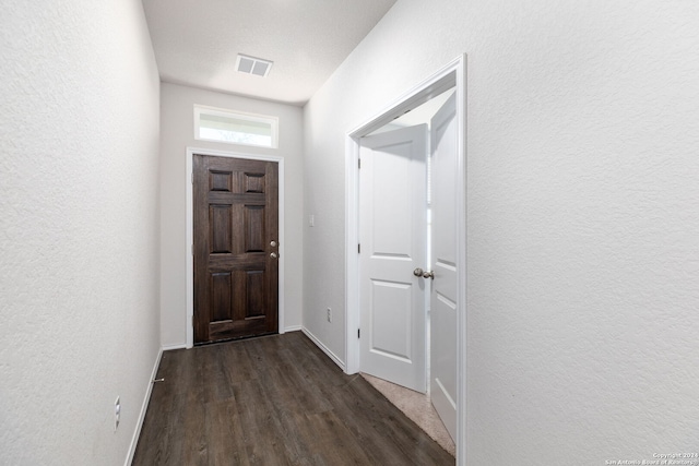 doorway with a textured ceiling and dark wood-type flooring