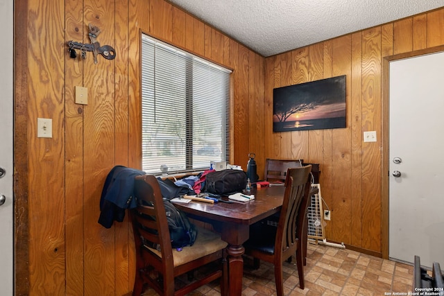 dining room featuring a textured ceiling and wooden walls