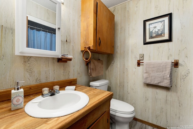 bathroom with vanity, toilet, and a textured ceiling