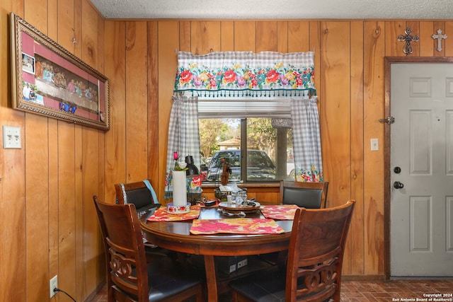 dining space featuring wood walls and a textured ceiling