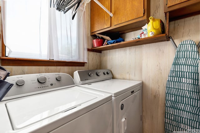 washroom with wooden walls, cabinets, and independent washer and dryer