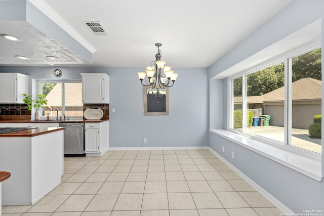 kitchen with stainless steel dishwasher, decorative backsplash, white cabinets, and a notable chandelier