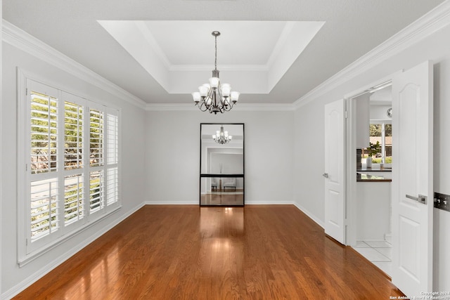 unfurnished dining area featuring crown molding, plenty of natural light, wood-type flooring, and an inviting chandelier