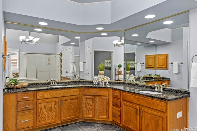 bathroom with a notable chandelier, a shower with door, and vanity