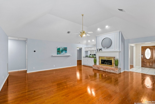 unfurnished living room featuring ceiling fan, a fireplace, light hardwood / wood-style floors, and lofted ceiling